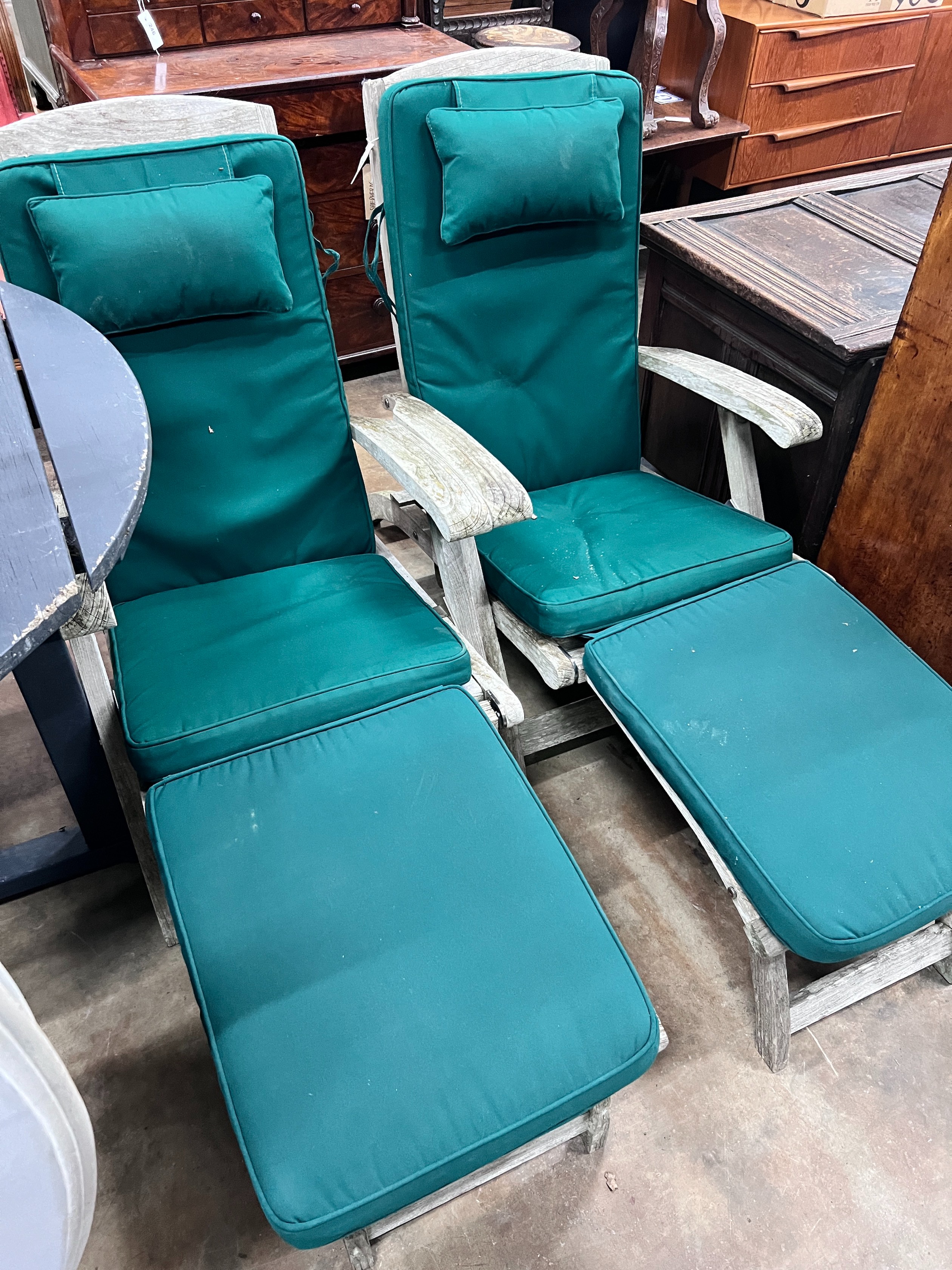 A pair of Indian Ocean weathered teak Burnham steamer chairs with green fabric squab cushions *