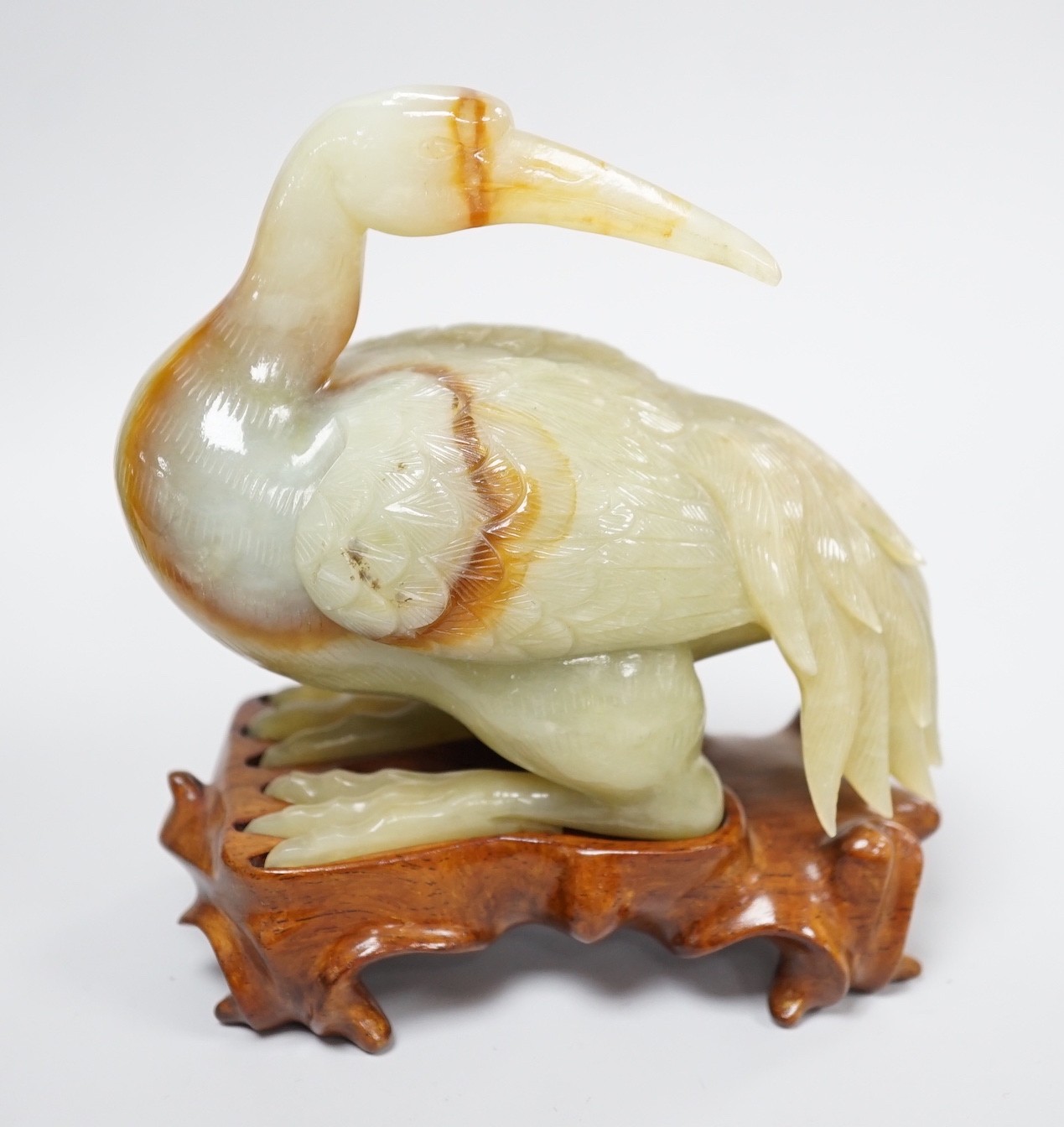 A Chinese green and russet jade figure of a crane, 11.5cm long, wood stand Provenance - the former