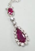 A modern 750 white metal, two stone ruby and fifteen stone diamond set pear shaped drop pendant