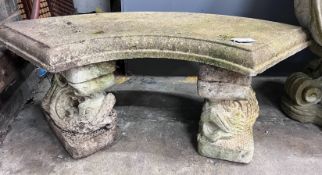 A reconstituted stone curved garden bench with dolphin supports, length 98cm, depth 46cm, height