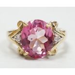 A modern 9ct gold and single stone oval cut flamingo topaz dress ring with two stone diamond set