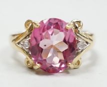 A modern 9ct gold and single stone oval cut flamingo topaz dress ring with two stone diamond set