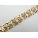 A modern pierced yellow metal and blue paste set bracelet, 19cm gross weight 28.2 grams.