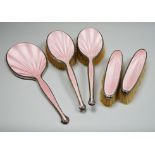 A George V five piece silver and pink guilloche enamel dressing table mirror and brush set, by