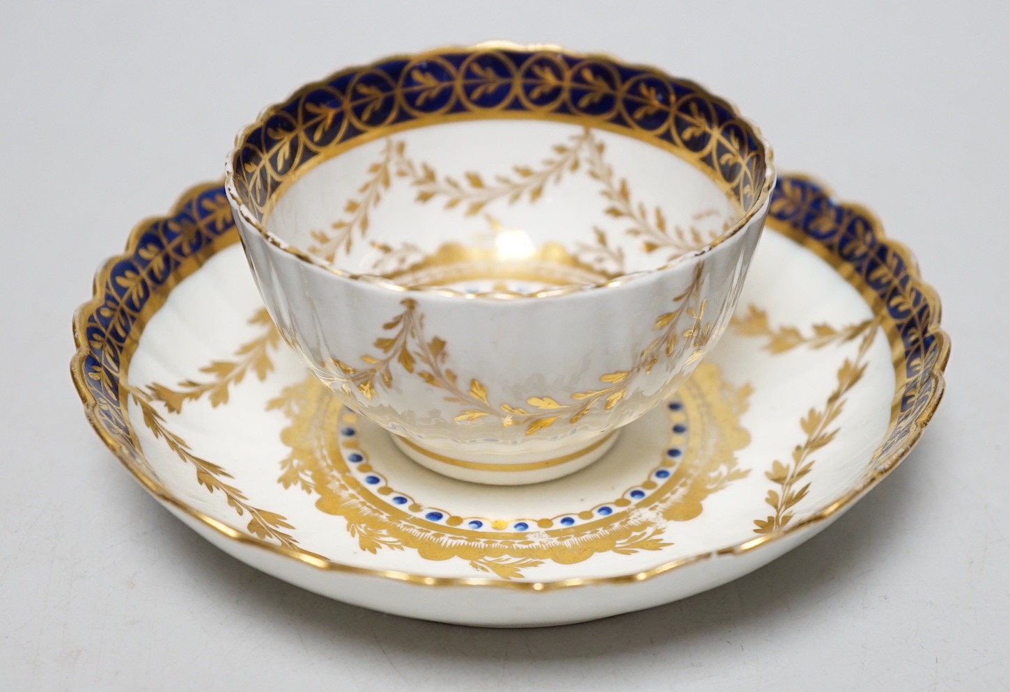An 18th century Caughley rare teabowl and saucer painted with a crest of an arm clutching a dragon