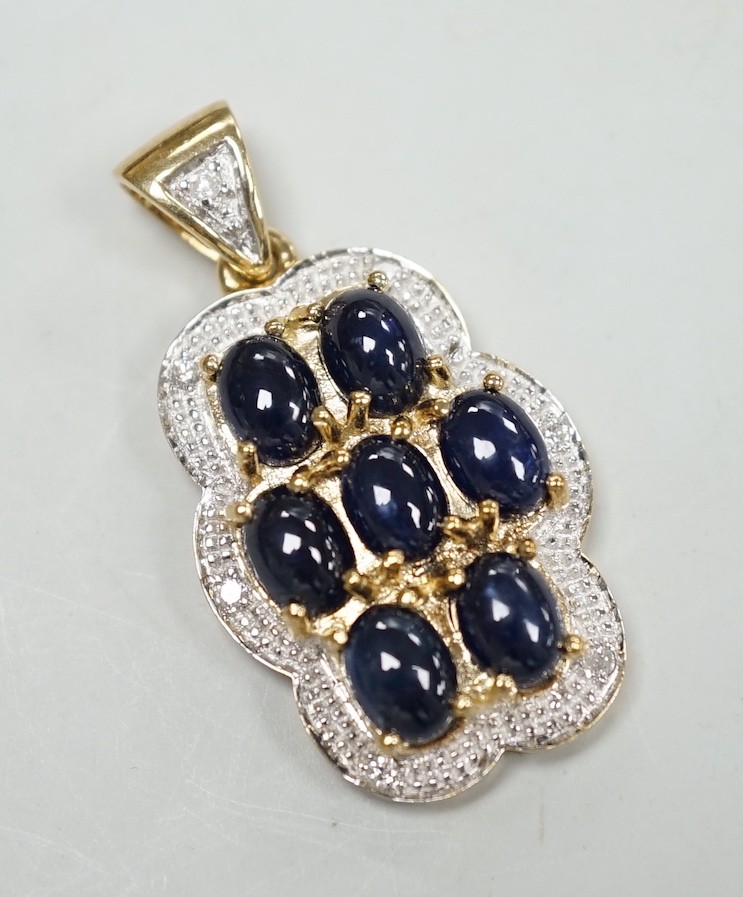 A modern 9ct gold, cabochon sapphire cluster and diamond chip set shaped oval pendant, overall 37mm,
