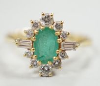 A modern 18ct gold, single stone oval cut emerald and round and baguette cut diamond cluster set