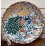 A Japanese enamelled porcelain ‘peacock’ dish on hardwood stand, dish 41cm diameter