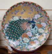 A Japanese enamelled porcelain ‘peacock’ dish on hardwood stand, dish 41cm diameter