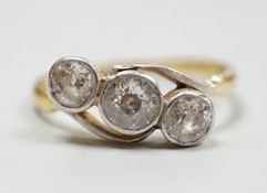 A yellow metal and three stone diamond set crossover ring, size N/O, gross weight 3.1 grams.