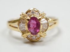 A modern 18ct gold, single stone ruby and trapeze and round cut diamond cluster set dress ring, size