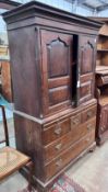A George III oak press cupboard with two panelled doors over five drawers, width 111cm, depth