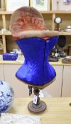 An early 20th century 'Prima Donna' red velvet corset mannequin on turned stand with a