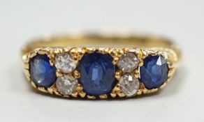 A late Victorian 18ct gold and three stone sapphire set ring, with four stone diamond set spacers,