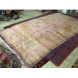 An antique Donegal carpet, with scrolling motifs on a pale, pink ground, cut and reduced in size,