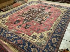 A Persian style pink ground carpet with field of foliate, motifs, multi bordered, 351 x 291cm