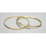 Two modern 750 yellow metal hinged bangles, one with diamond set twin hearts motif, gross weight