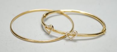 Two modern 750 yellow metal hinged bangles, one with diamond set twin hearts motif, gross weight