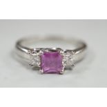 A modern platinum, single stone square cut pink sapphire and two stone diamond set ring, size N/O,