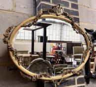 An Edwardian oval giltwood and gesso wall mirror with ribbon and flower swagged border, width