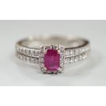 A modern 18ct white gold, single stone emerald cut ruby and diamond chip set cluster ring, with