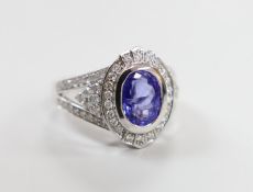 A modern 14k white metal, oval cut tanzanite and diamond chip set cluster dress ring, with diamond
