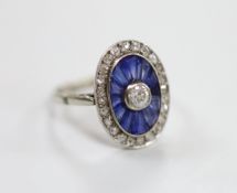 A 1920's white metal, sapphire and diamond oval cluster ring, set with round cut diamonds and shaped