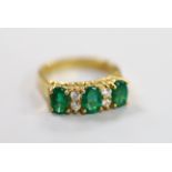 A 750 yellow metal, three stone emerald and four stone diamond spacer set half hoop ring, size K,