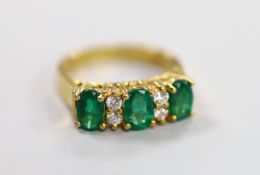 A 750 yellow metal, three stone emerald and four stone diamond spacer set half hoop ring, size K,
