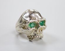 A white metal (tests a silver) and two stone emerald set skull ring, size T/U, gross weight 35,2