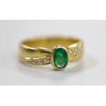 A modern 18ct gold and single stone oval cut emerald ring, with six stone diamond set shoulders,