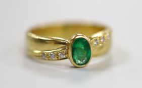 A modern 18ct gold and single stone oval cut emerald ring, with six stone diamond set shoulders,