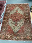 An Isphahan red and cream medallion rug, enclosed by a border of trailing stylised foliage, 200cm