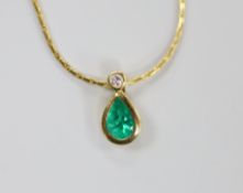 A modern 18ct gold, pear cut emerald and round cut diamond set pendant, 14mm, on an 18ct gold chain,