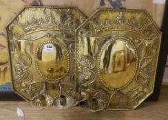 A pair of brass wall sconces, each with embossed reflector backplates supporting two branches, one