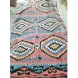 A pink ground flat weave Kilim rug woven with three rows of lozenges, approx. 240 x 160cm