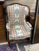 A Louis XV Provincial walnut wing armchair, with moulded frame, arched stuffed back loose cushion
