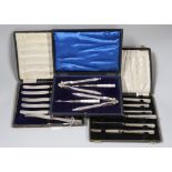 Two cased sets of six silver handled cake knives and cased plated nutcracker set.