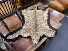 An early 20th century taxidermy leopard rug with head, felt backed, later lining, length 190cm