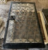 A heavy wrought and cast iron wine cellar security door and lock, with a plate glass inset panel,