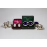 Two cased pairs of silver condiments including chased pepperettes, 45mm and four other silver