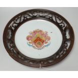 An 18th century Chinese armorial dish, rim cut down and mounted in a 19th century English mahogany