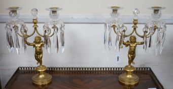 A pair of Regency ormolu ‘Cupid’ two branch glass lustre candelabra, 37cm high
