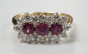 A modern 18ct gold, ruby and diamond set triple cluster ring, size L, gross weight 3.3 grams.