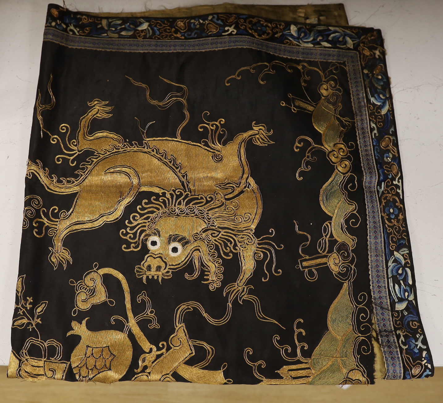 A 19th century Chinese dark blue ground panel, gilt thread embroidered with a pair of celestial - Image 2 of 2