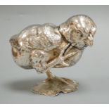 A novelty white metal pepperette, modelled as a chick on one leg, scratching, height 89mm.