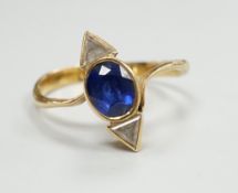 A yellow metal and single stone oval cut sapphire and two stone triangular cut diamond set ring,