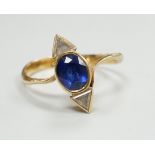 A yellow metal and single stone oval cut sapphire and two stone triangular cut diamond set ring,