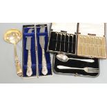 Three cased sets including silver cocktail sticks, two boxed bread knives and a sterling ladle.