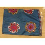 An early 20th century Suzani hanging, embroidered with red pink and gold foliate designs, on blue